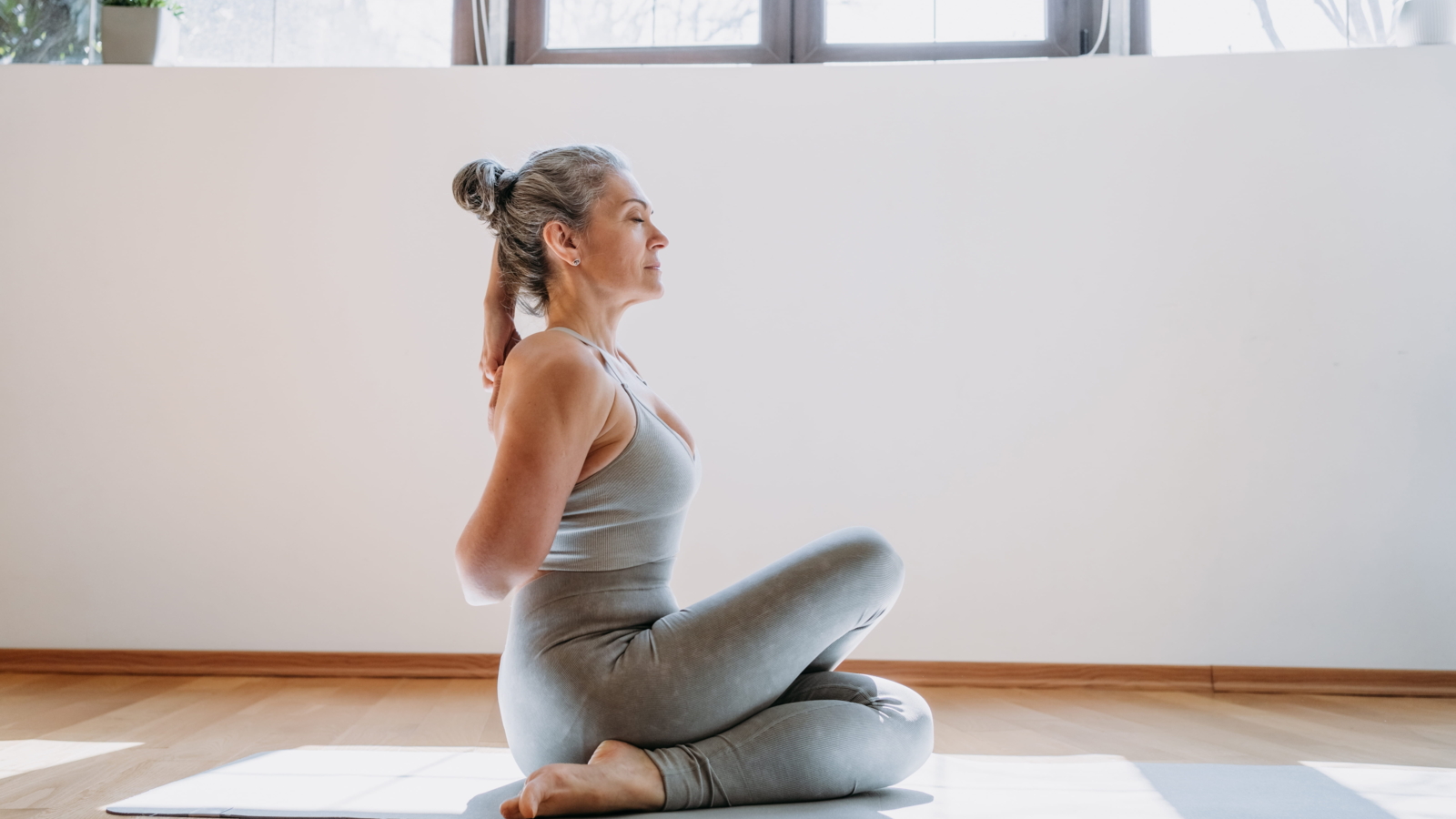 Woman sitting calmly on a yoga mat, practicing gentle stretching with focus and control