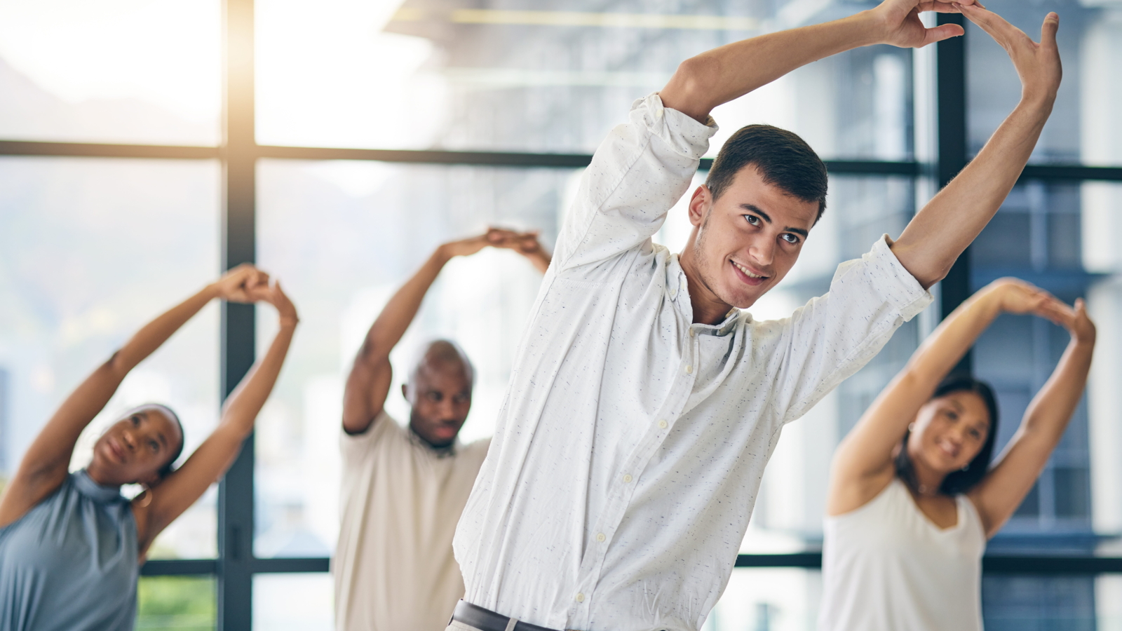 group of office employees doing side stretches together as part of a workplace movement break routine