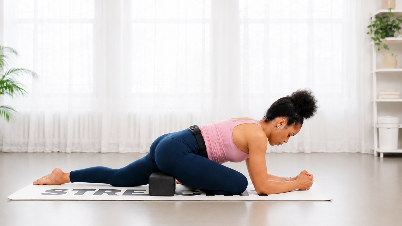 Woman practicing a supported pigeon stretch with a yoga block under the hip to improve comfort, alignment, and hip mobility.