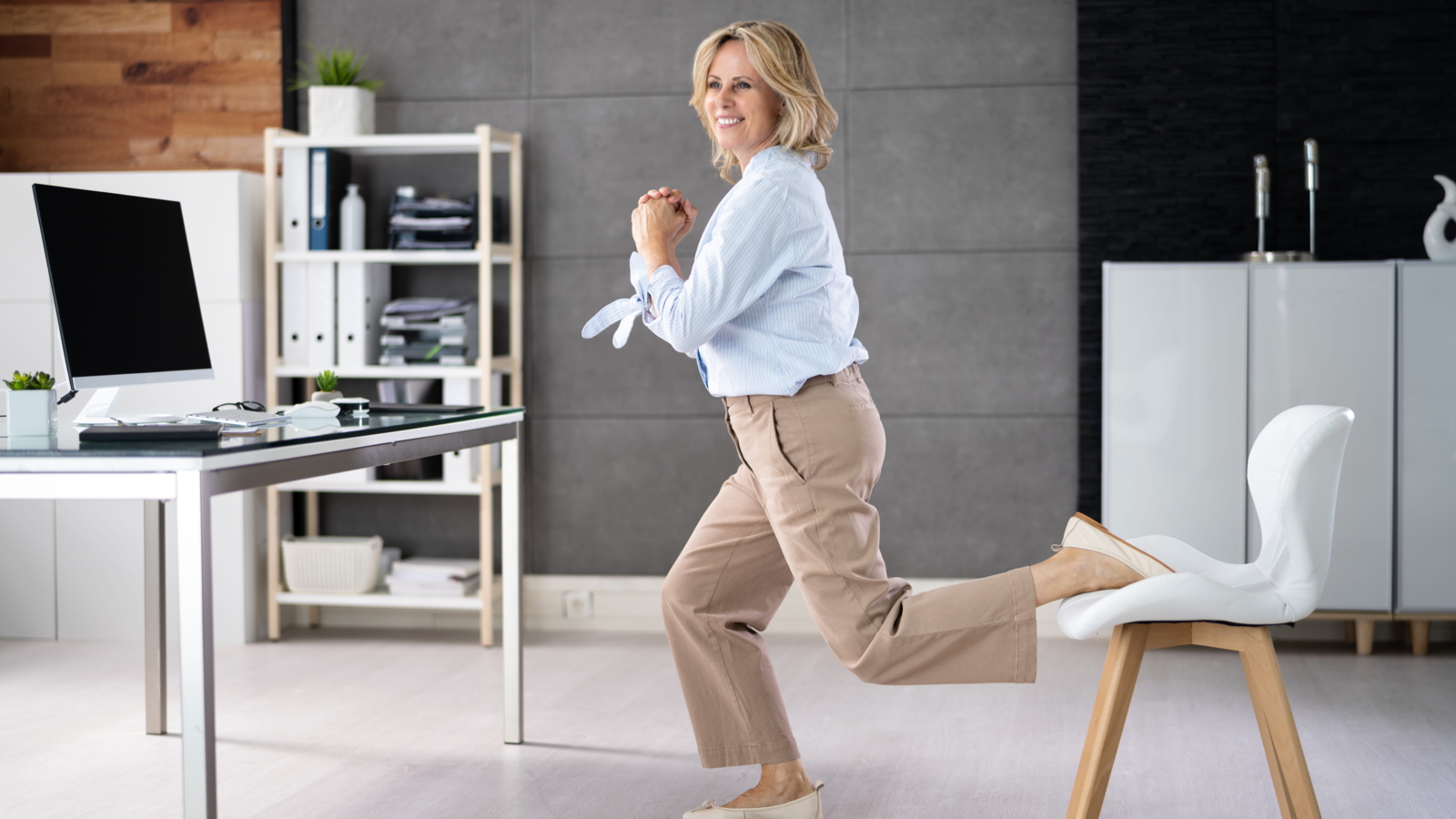 woman doing a split squat using a chair in an office as a quick movement break exercise for strength and mobility