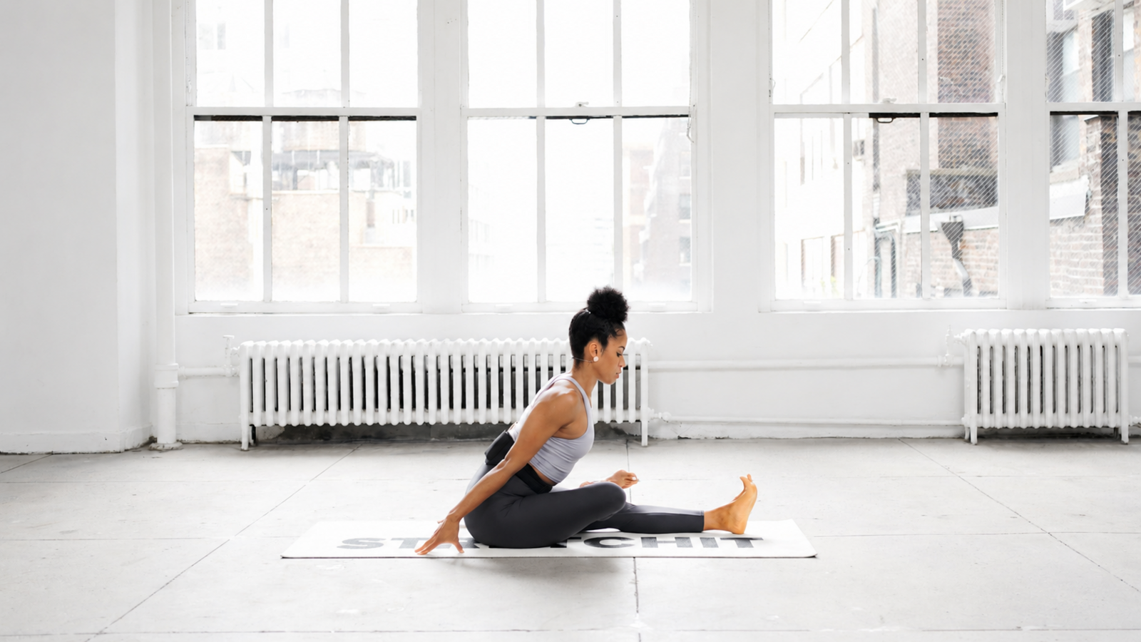 STRETCHIT trainer Alicia Archer practicing a seated hip mobility stretch with one leg extended STRETCHIT trainer Alicia Archer practicing a seated hip mobility stretch with one leg extended